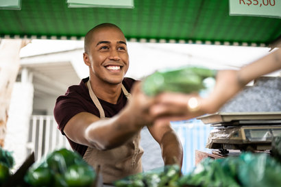 Vendor hands a fruit to customer